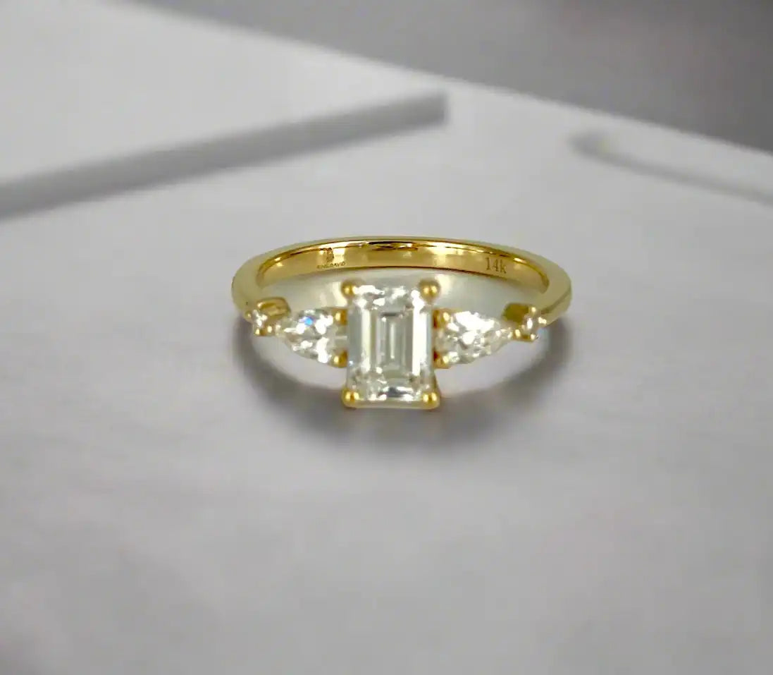 Gold ring with a central diamond and two smaller diamonds on a white background