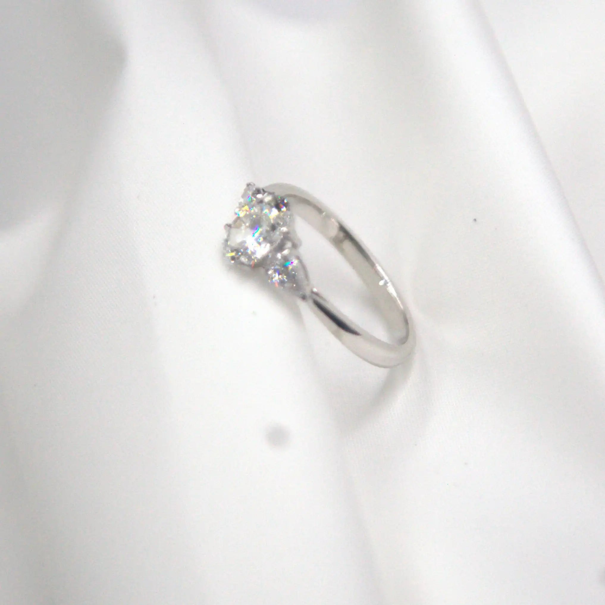 Eglah Engagement Ring with oval-cut diamond set in 14K white gold on white silk background