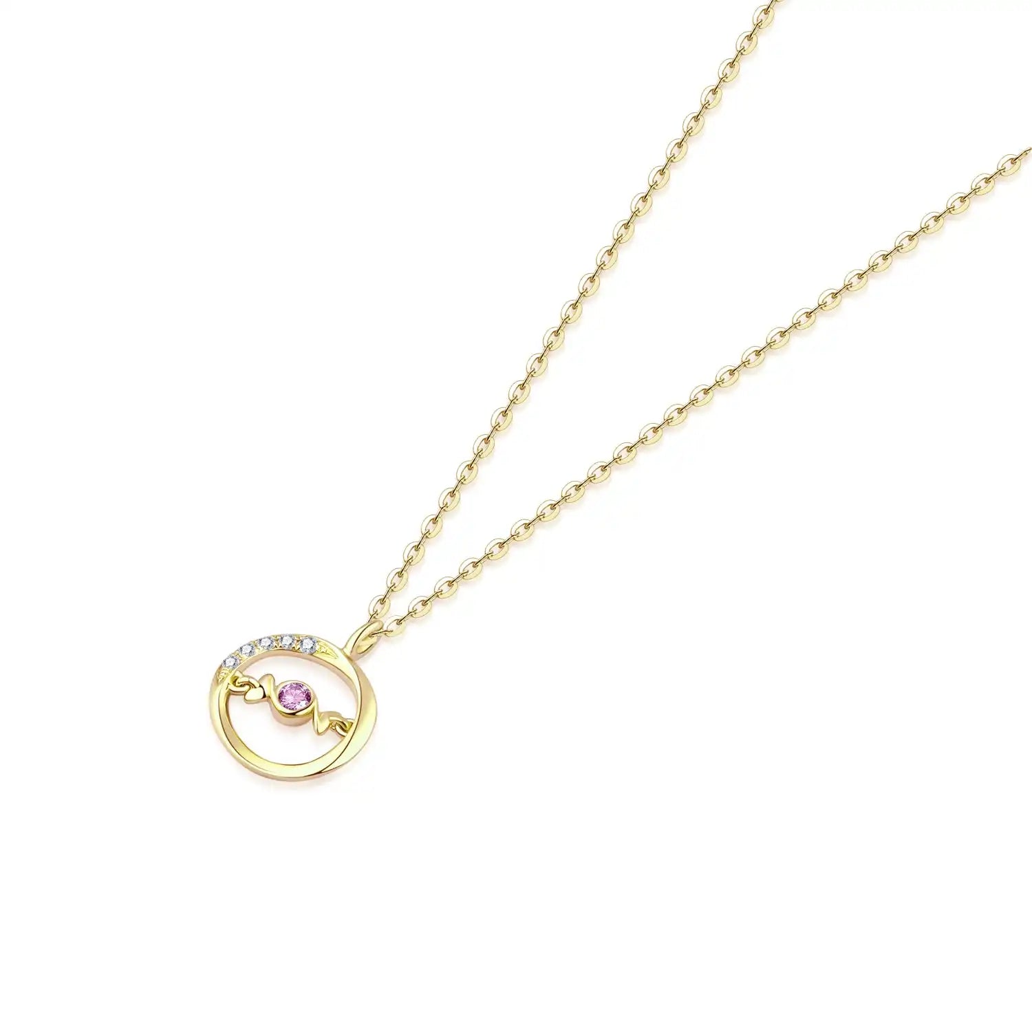 A delicate 18K yellow gold necklace with a circular pendant featuring a round pink sapphire in the center and a curved row of small white diamonds on one side. The pendant hangs from a thin gold chain.