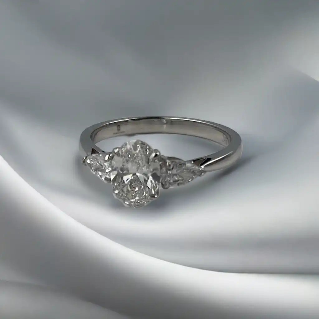 Eglah Engagement Ring with oval-cut diamond set in 14K white gold on white silk background