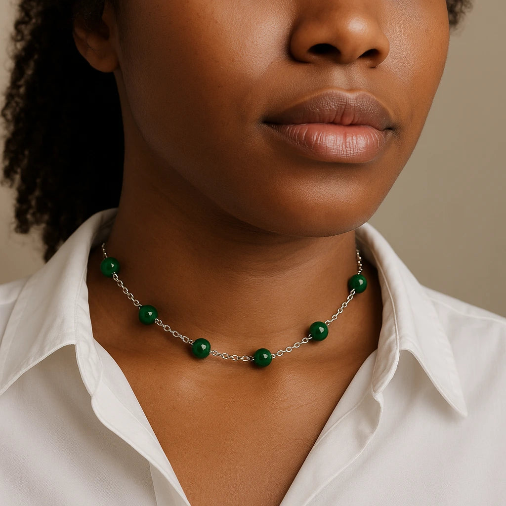 Close-up of a person wearing a malachite green beaded necklace with a neutral background