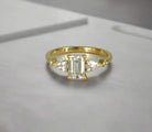 Gold ring with a central diamond and two smaller diamonds on a white background