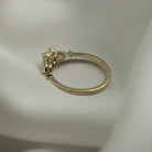 Haggith Engagement Ring with emerald-cut diamond and two side stones on 14K yellow gold band resting on soft white silk